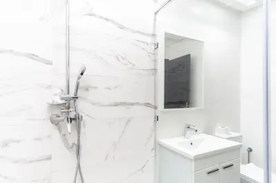 a white bathroom with a shower and a sink at Beautiful central apartment in Marrakech