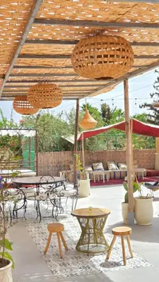 a patio with tables and benches and a wooden ceiling at Guesthouse Better Together in Marrakech