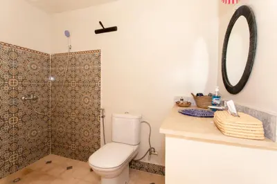 a bathroom with a toilet and a shower with a mirror at Guesthouse Better Together in Marrakech