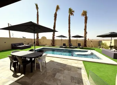 a patio with a table and chairs and a pool with palm trees at Villa Marrakech DAR JAHYR in Douar Ouled Ahmed