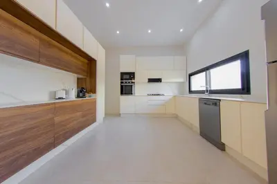 a large kitchen with wooden cabinets and a window at Beautiful new villa with private pool in El Rhechat