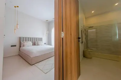 a bedroom with a bed and a walk in shower at Beautiful new villa with private pool in El Rhechat