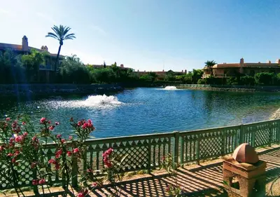 a pond with a fence and flowers in front of it at L'Oasis Chic Palmeraie Marrakech Piscine & Petit Déj Offert in Marrakech
