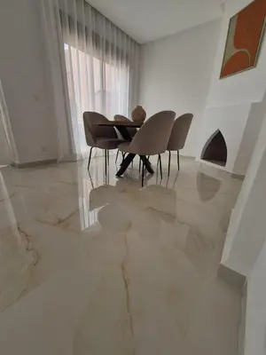 a dining room with a table and chairs on a marble floor at Sumptuous apartment in Premium Village in Marrakech