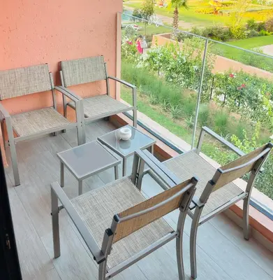 three chairs and a table on a balcony with a view at Cozy appartement à noria golf in Marrakech