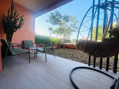a patio with a swing and a table and chairs at Cozy appartement à noria golf in Marrakech