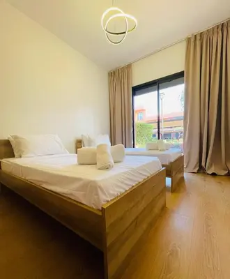 a bedroom with two beds and a large window at Cozy appartement à noria golf in Marrakech