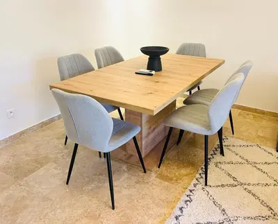 a wooden table with four chairs and a vase on it at Cozy appartement à noria golf in Marrakech