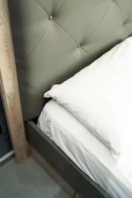 a bed with a padded headboard and white sheets at Cozy apartment in the hypercenter in Marrakech