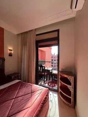 a bedroom with a bed and a balcony with a table at Marrakech Apartment Hivernage in Marrakech