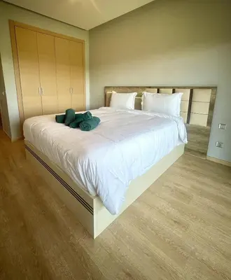 a large white bed with a teddy bear on it at Superb apartment with all amenities and pool in Marrakech