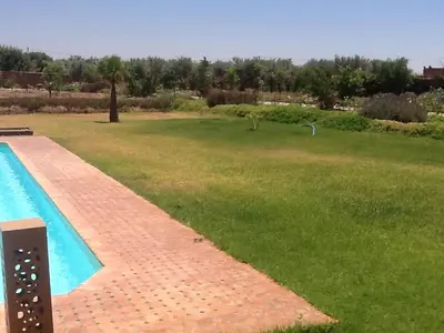 a backyard with a swimming pool and a field of grass at Domaine VILLA in Marrakech