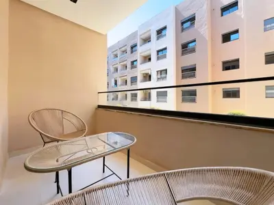 a balcony with two chairs and a table and a building at Menara Garden Wifi Parking Piscine in Marrakech