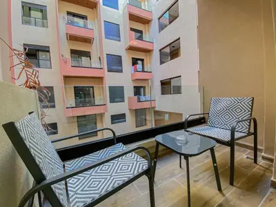 a balcony with two chairs and a table and a building at Stylish Hivernage Studio in Marrakech