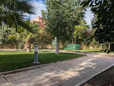 a park with a bench and a tree and grass at Le Cocon Nature in Marrakech