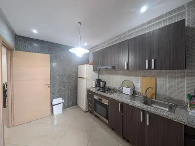a kitchen with wooden cabinets and a white refrigerator at Le Cocon Nature in Marrakech