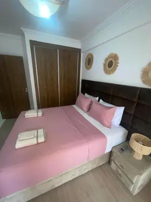 a bedroom with a large bed with pink sheets and pillows at Two bedroom apartment - Guéliz train station in Marrakech