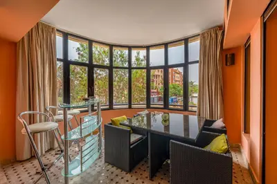 an orange room with a table and chairs and a large window at Marrakech GUELIZ Vue Imprenable et Terrasse rare in Marrakech