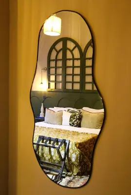 a mirror hanging on a wall with a bed at DAR MA ITTO Charming luxurious Medina Cocoon in Marrakech