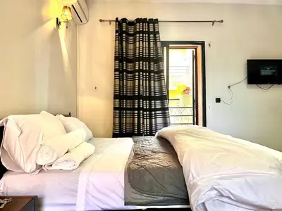 a bedroom with a bed with white sheets and a window at Nelbrj Studio in Marrakech