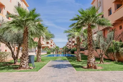 a resort with palm trees and a swimming pool at 2 bedrooms appartement les palmiers de targa in Marrakech
