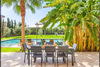 a dining table and chairs in front of a pool at Family villa in Marrakech in Marrakech