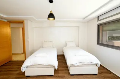 two beds in a room with white walls at Bonheur appartement in Marrakech
