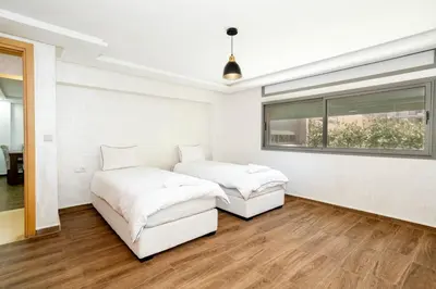 two beds in a white room with a window at Bonheur appartement in Marrakech