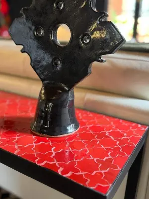 a black vase sitting on a red table at Villa ÈME in Marrakech