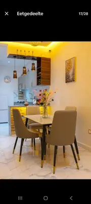 a dining room table with chairs and a vase of flowers at Appartement limoen in Marrakech