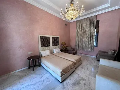 a bedroom with a large bed and a chandelier at Villa de Charme avec Piscine, Hammam & Jardin Enchanté in Marrakech