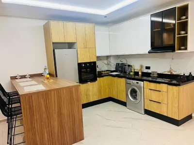 a kitchen with wooden cabinets and a washer and dryer at Monolocale l'alba Hevernage 1ch in Marrakech