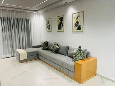 a living room with a gray couch and paintings on the wall at Monolocale l'alba Hevernage 1ch in Marrakech