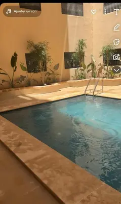 a swimming pool with blue water in a building at L'aube de l'éveinage 2 bedrooms Marrakech station in Marrakech