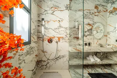a bathroom with a shower with marble walls at Villa Traverta Marrakech, 5 Suites, Heated Pool, Workation & Authentic Hammam in Marrakech