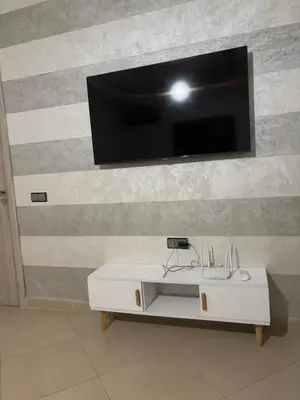 a living room with a tv and a white table at cozy and warm apartment in Marrakech
