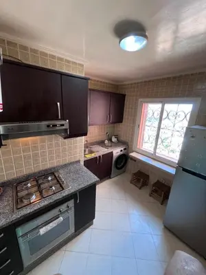 a kitchen with brown cabinets and a sink and a refrigerator at Darhome in Marrakech