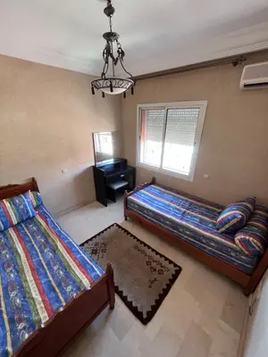 a bedroom with two beds and a desk and a chandelier at Darhome in Marrakech