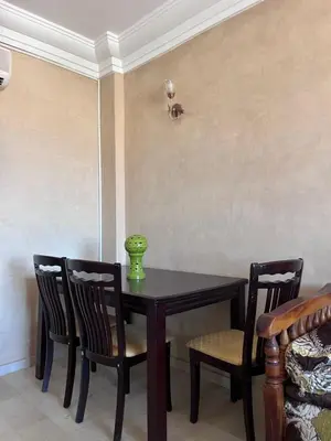 a dining room table with two chairs and a green vase on it at Darhome in Marrakech