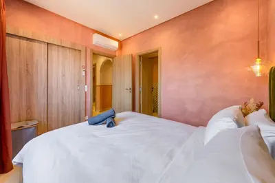a bedroom with a large white bed with wooden walls at Villa Cõrdõba piscine chauffée et sans vis-à-vis in Marrakech
