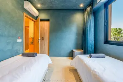 two beds in a room with a window at Villa Cõrdõba piscine chauffée et sans vis-à-vis in Marrakech