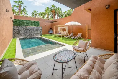 a patio with a pool and chairs and a table at Villa Cõrdõba piscine chauffée et sans vis-à-vis in Marrakech