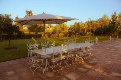 a table with chairs and an umbrella at Palais Soufi 8 chambres in Marrakech