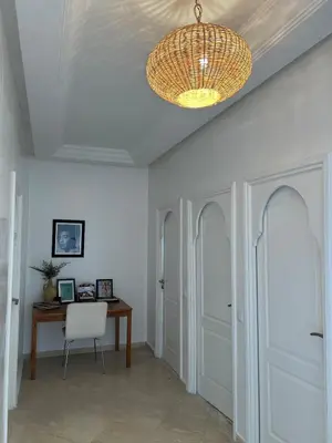 a hallway with a table and a chandelier at Residence La Perle de Atlas Appartement in Marrakech