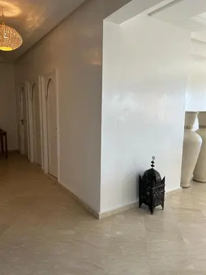 a room with a white wall and a black chair at Residence La Perle de Atlas Appartement in Marrakech