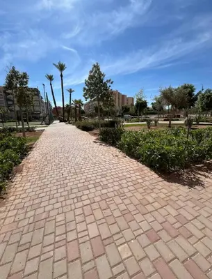 a brick road in a park with palm trees at Yumo - Cozy 3 in Marrakech
