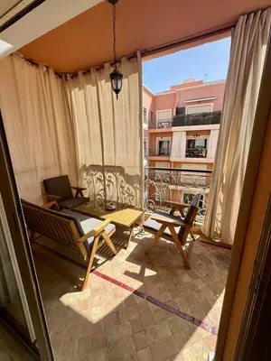 a room with a balcony with a table and chairs at Elegant 2BR, Pool & Gym Access in Marrakech