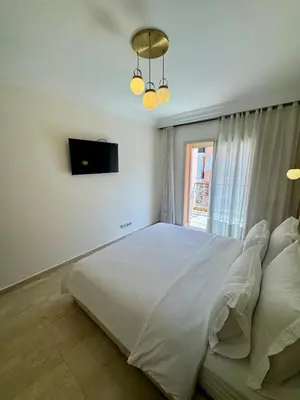 a bedroom with a large white bed and a television at Elegant 2BR, Pool & Gym Access in Marrakech