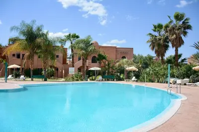 a large swimming pool with palm trees and a building at Marrakxi in Marrakech