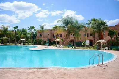 a large swimming pool in a resort with palm trees at Marrakxi in Marrakech